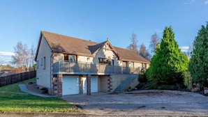 Ein zweistöckiges Haus mit Balkon, Garage und Auffahrt.