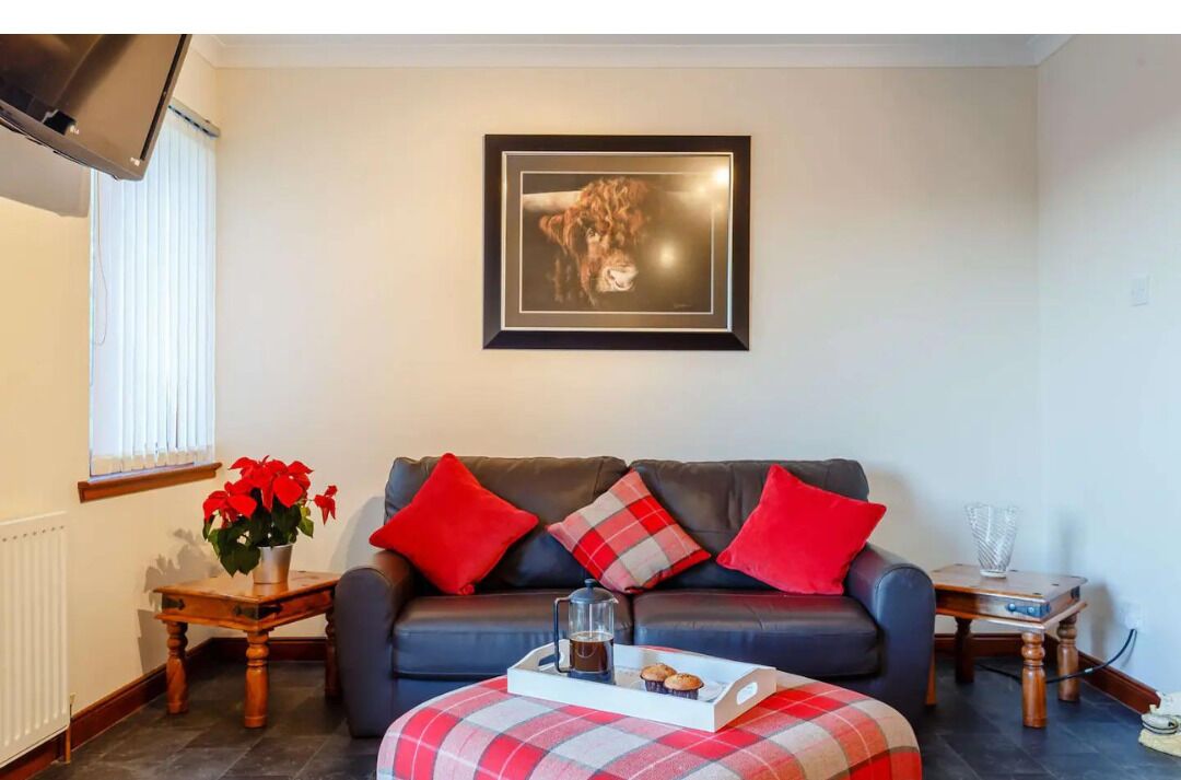 A living room with a sofa, a coffee table, a framed picture on the wall, and a window with blinds.