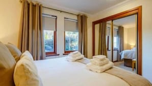 Ein Hotelzimmer mit einem großen Bett, zwei Vorhängen und einem Spiegel sowie einer Tür.