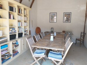 Een eetgedeelte met een houten tafel, zachte stoelen en boekenkasten vol boeken en gezelschapsspellen.