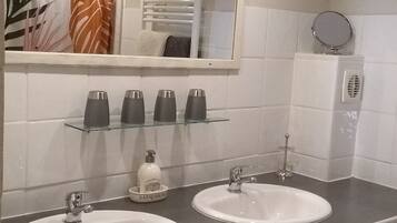 Ein Badezimmer mit zwei Waschbecken, einem Spiegel und einem Handtuchhalter.