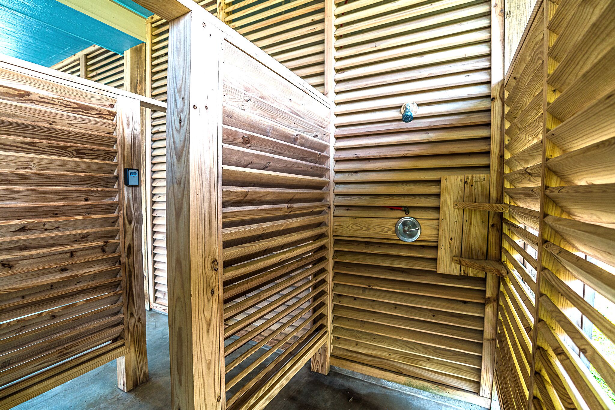 A wooden cabin with a slatted wall design, a metal door, and a small window.