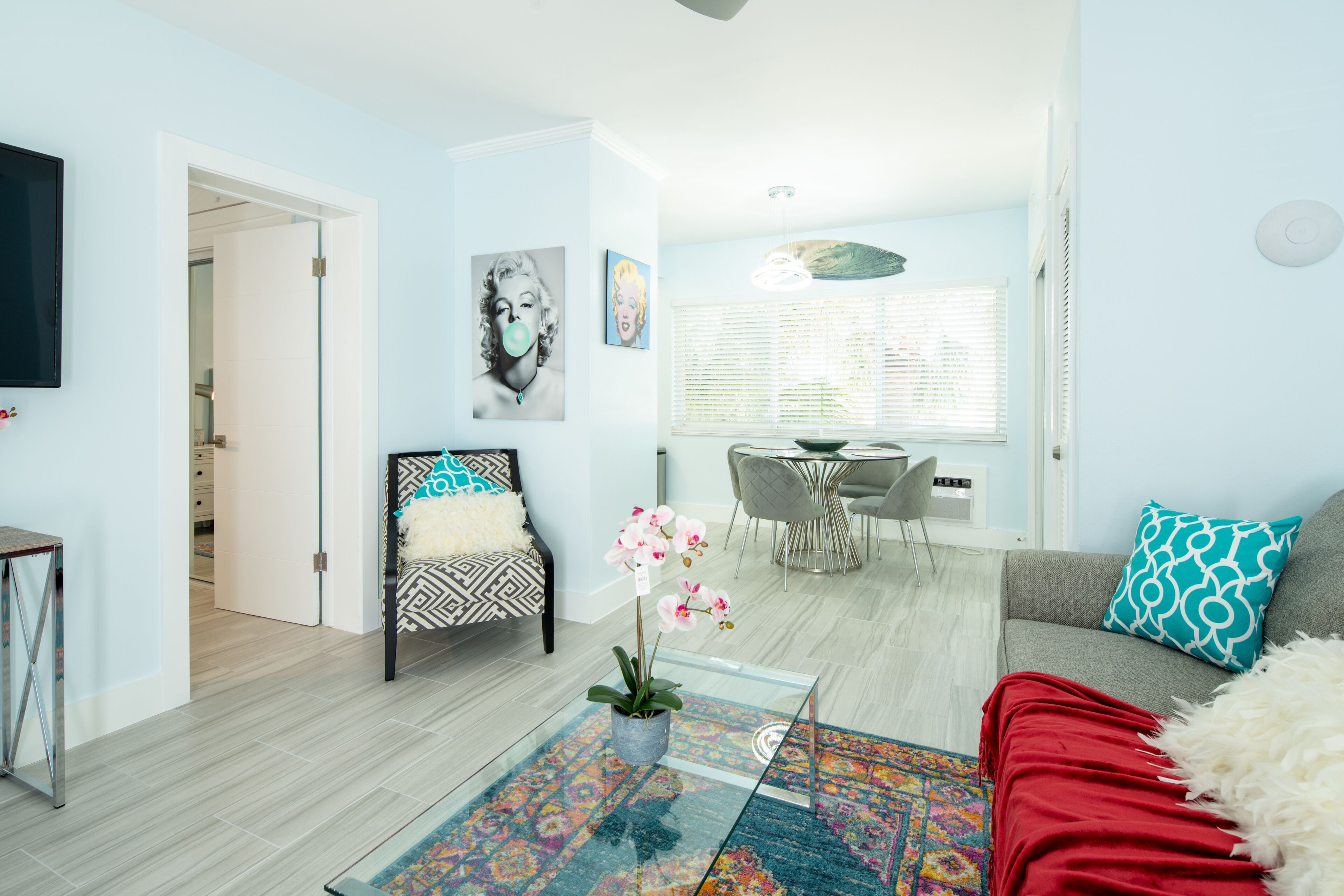 Un soggiorno moderno con divano, tavolino con una pianta, tappeto decorativo e zona pranzo con tavolo e sedie.