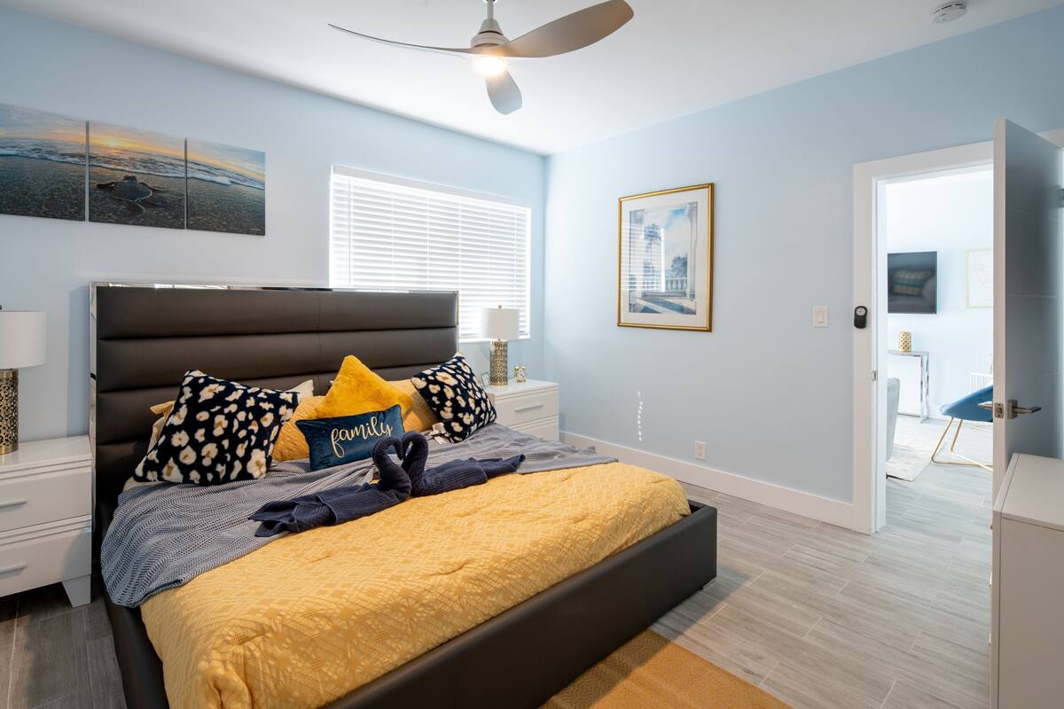 A bedroom with a bed, nightstands, a ceiling fan, and artwork on the walls.