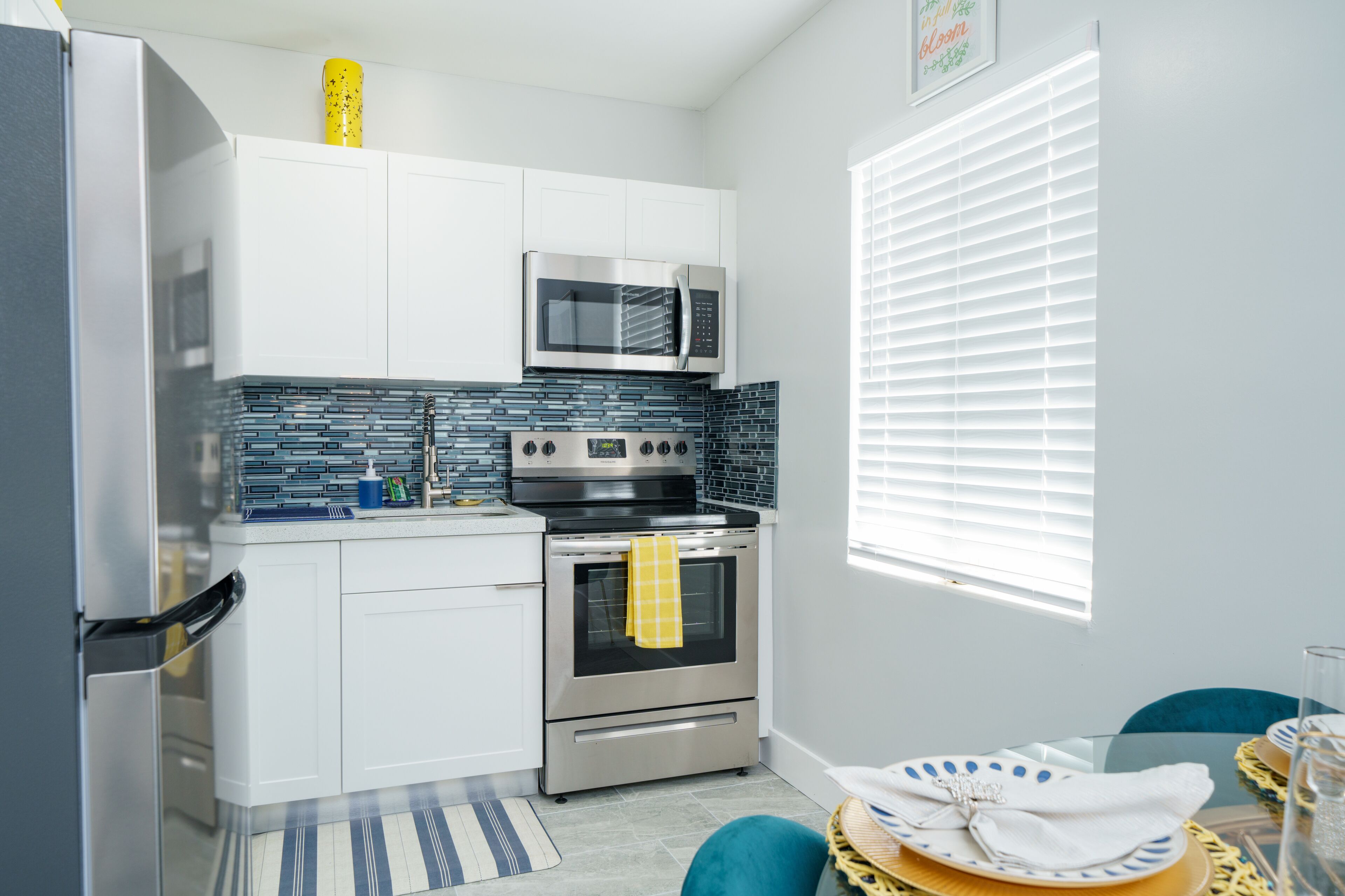 A modern kitchen with white cabinets, a stainless steel microwave, an oven, and a tiled backsplash.