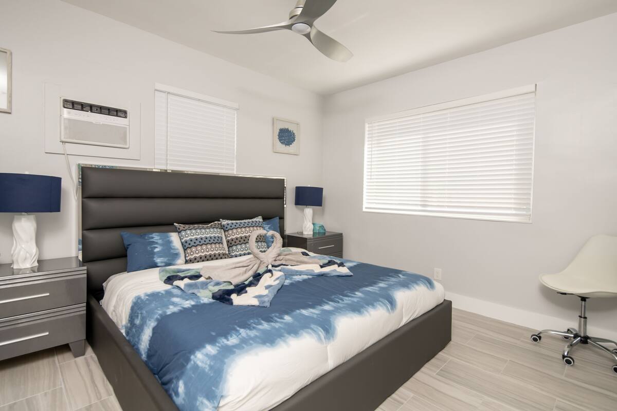 A bedroom with a bed, bedside tables, a ceiling fan, and a window with blinds.