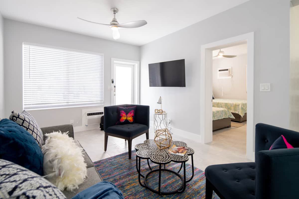 A modern living room with a sofa, armchairs, a coffee table, and a TV mounted on the wall.