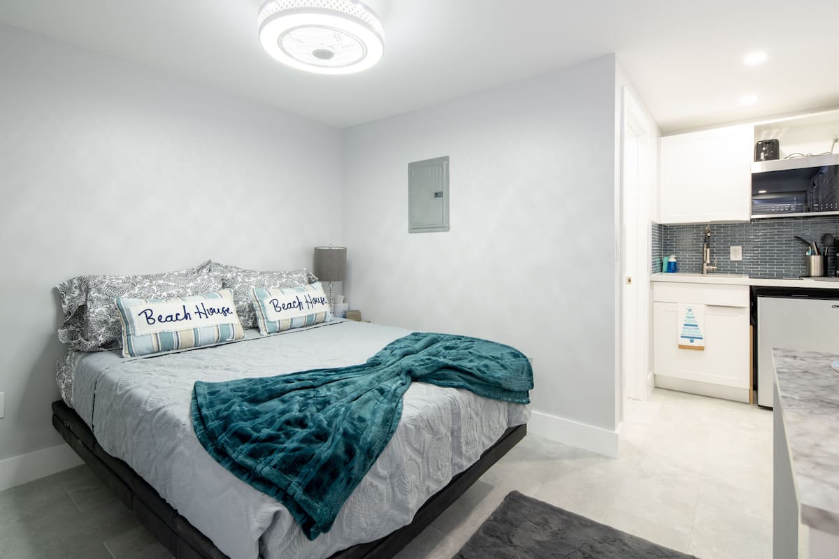 A bedroom with a bed, pillows, a blanket, a bedside table, and a nightstand.