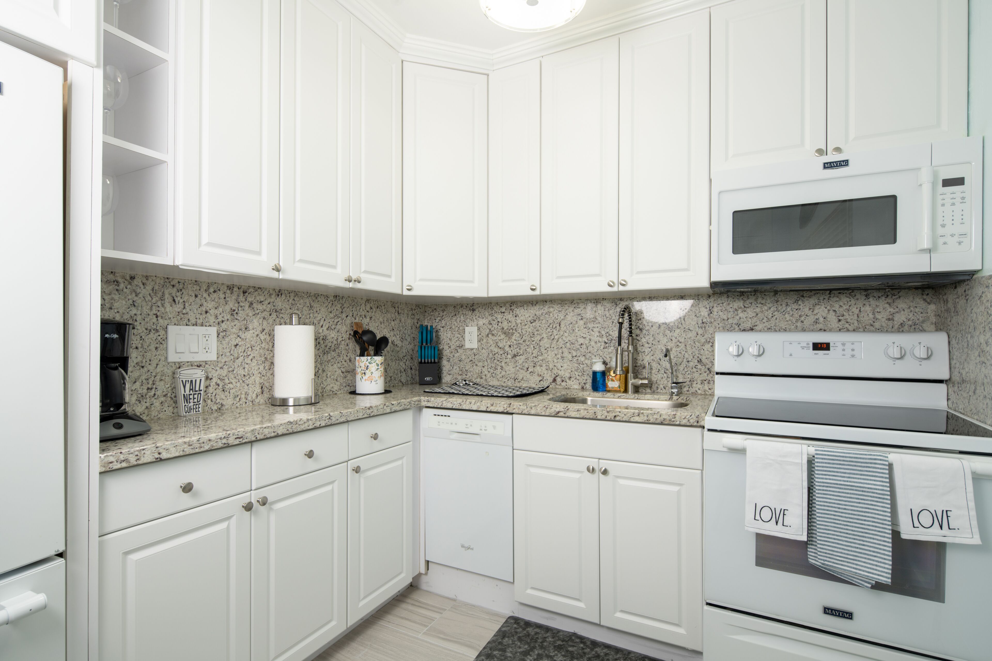 A modern kitchen with white cabinets, a microwave, an oven, and a dishwasher.