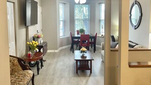 Een ruime woonkamer met een bank, een salontafel en een eethoek met een tafel en stoelen.