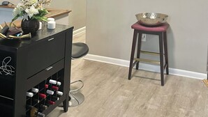 Een moderne woonkamer met een donker houten kast, een klein krukje en een abstract schilderij in een lijst aan de muur.