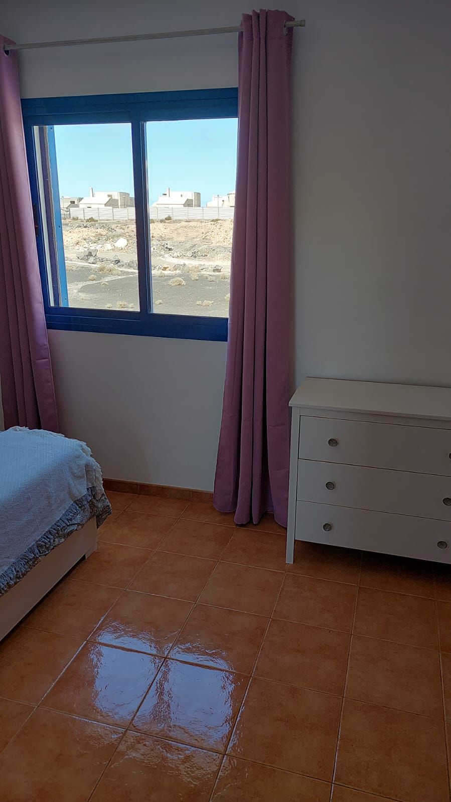 Ein Zimmer mit einem Bett, einem Schminktisch und einem Fenster mit Vorhängen.