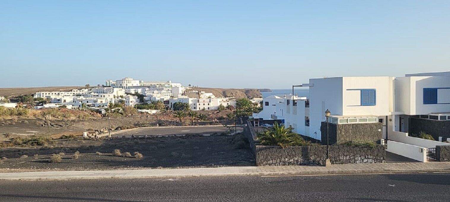 A coastal town with white buildings, a paved road, and a clear sky.
