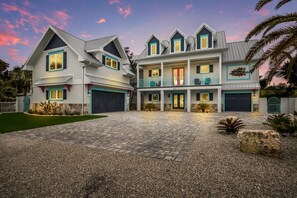 Une maison à deux étages avec une allée menant à une entrée fermée par un portail.