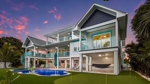 Ein zweistöckiges Haus mit Swimmingpool, mehreren Balkonen und einem gepflegten Rasen.