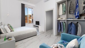 Un dormitorio moderno con una cama, un televisor, un armario y una zona de estar con un sofá azul.