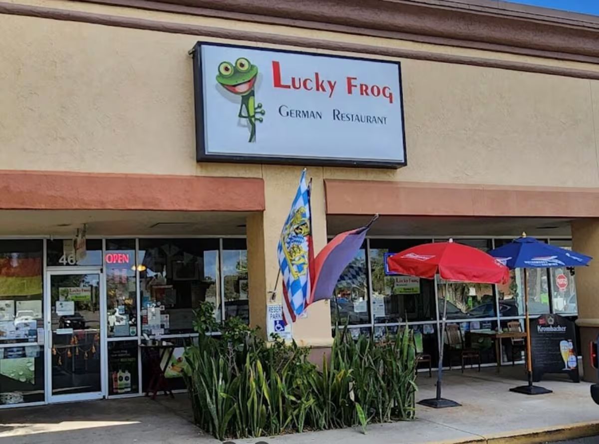 Liiketila, jonka edessä on kyltti, jossa lukee ”Lucky Frog German Restaurant”, ja lippu.
