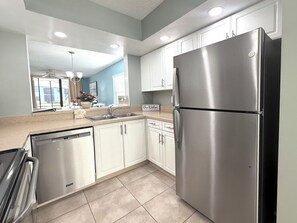 Una cocina moderna con electrodomésticos de acero inoxidable, armarios blancos y un ventanal con vistas.