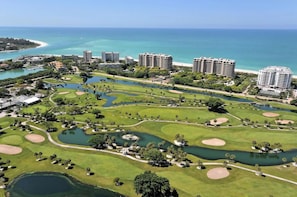 A golf course with multiple bunkers, water hazards, and a view of the ocean.