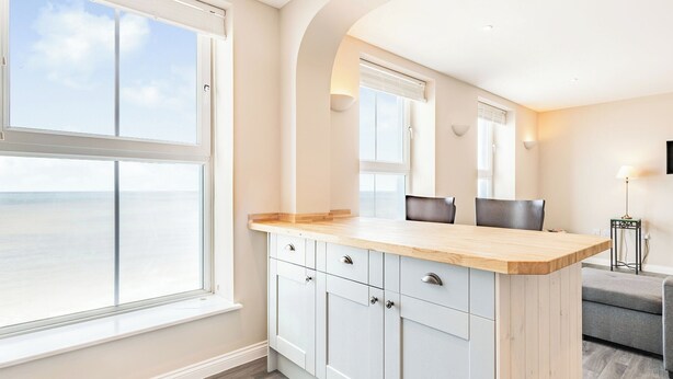 A modern kitchen with a large window, white cabinetry, and a wooden countertop. - Luxury apartments with sea and pier views, right in the heart of North Norfolk. (Cromer)