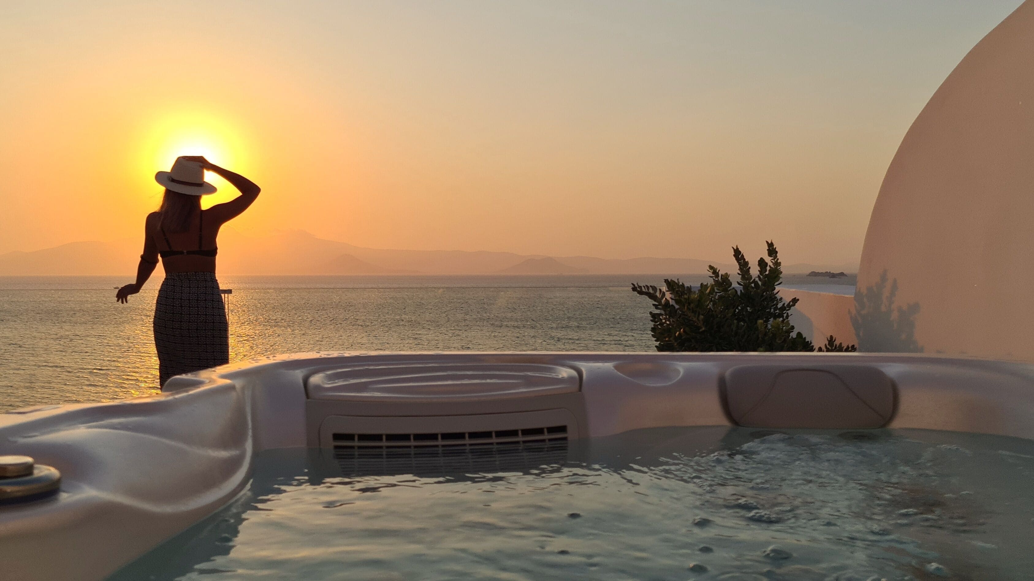 A person standing by a hot tub with a sunset view.