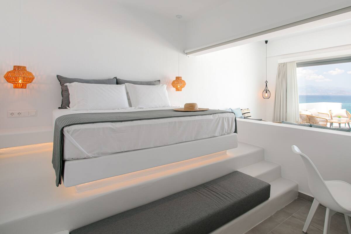Un dormitorio moderno con cama, mesita de noche y vistas al mar.