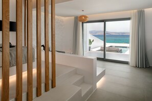 Une chambre d’hôtel moderne avec un escalier menant à un balcon offrant une vue sur la mer.