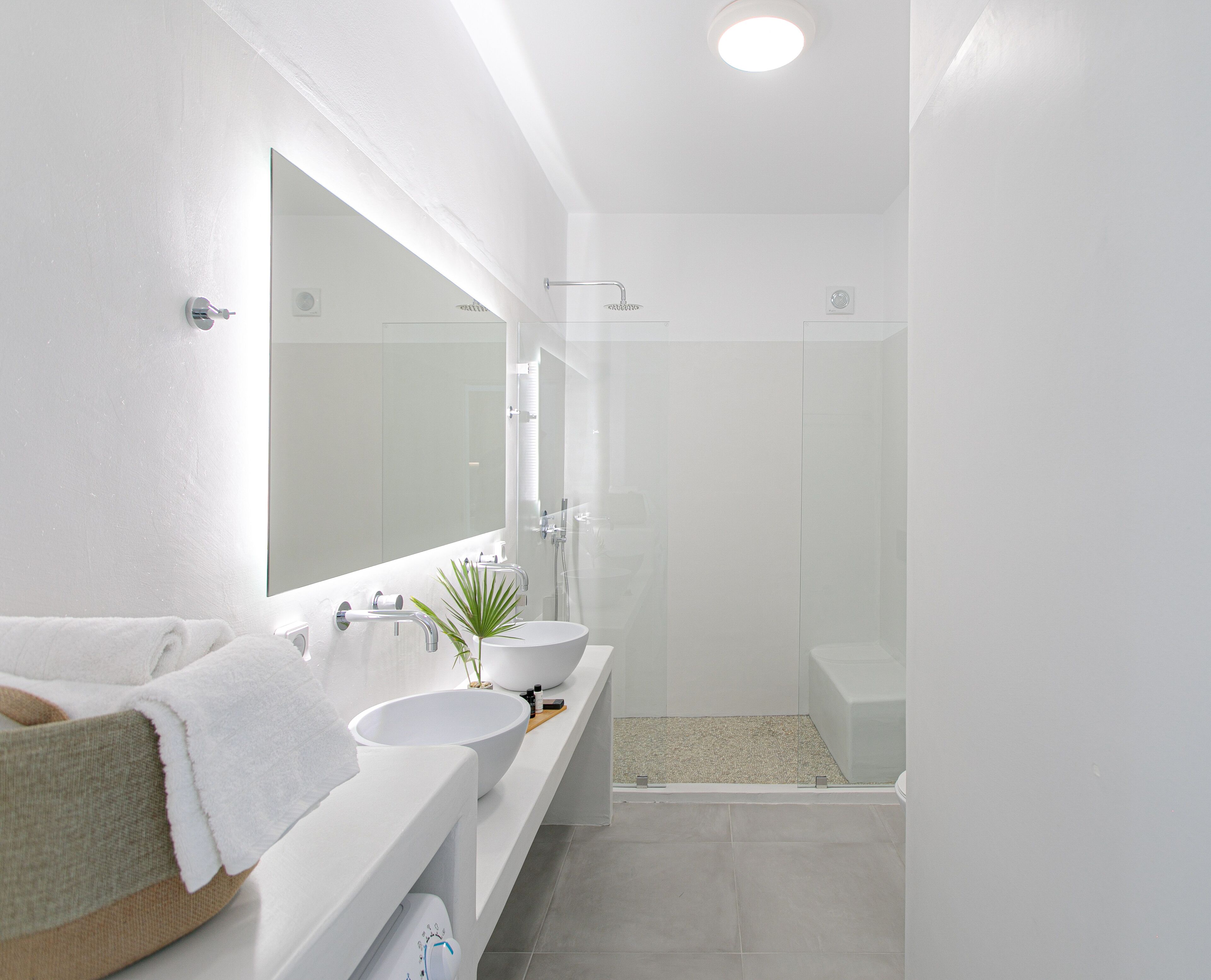 Une salle de bain moderne avec un grand miroir, deux lavabos, une douche et des toilettes.