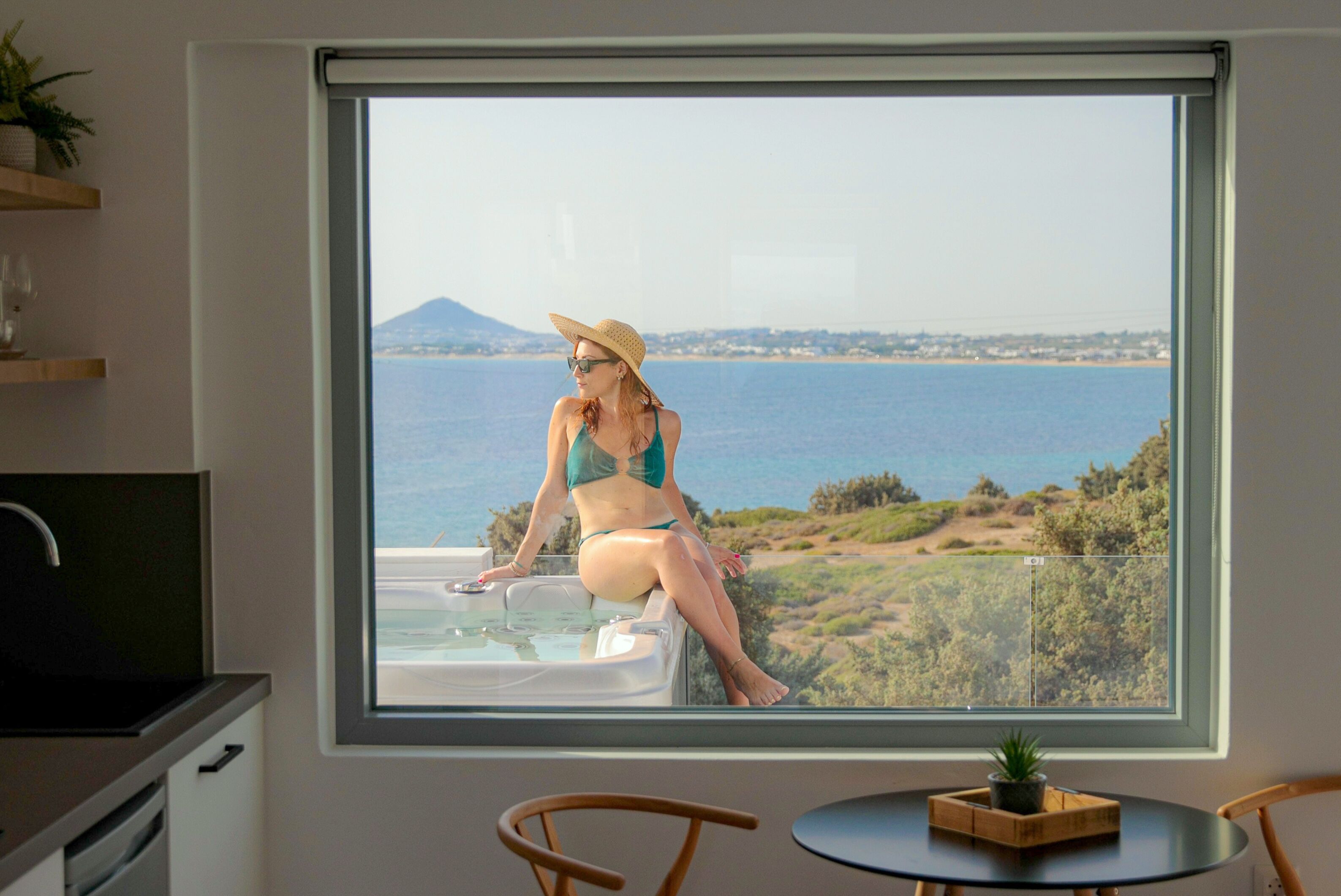 Una habitación con un ventanal grande que ofrece vistas panorámicas del mar y las colinas.