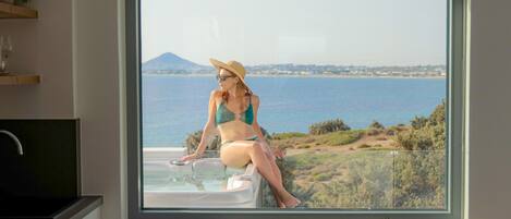 Una habitación con un ventanal grande que ofrece vistas panorámicas del mar y las colinas.