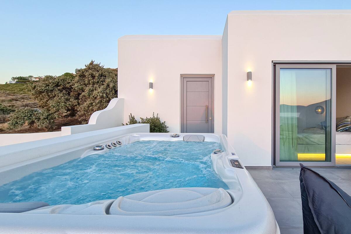 Un área moderna de hidromasaje al aire libre con vistas despejadas del paisaje circundante, una puerta que da a una habitación y una entrada de vidrio a un dormitorio.