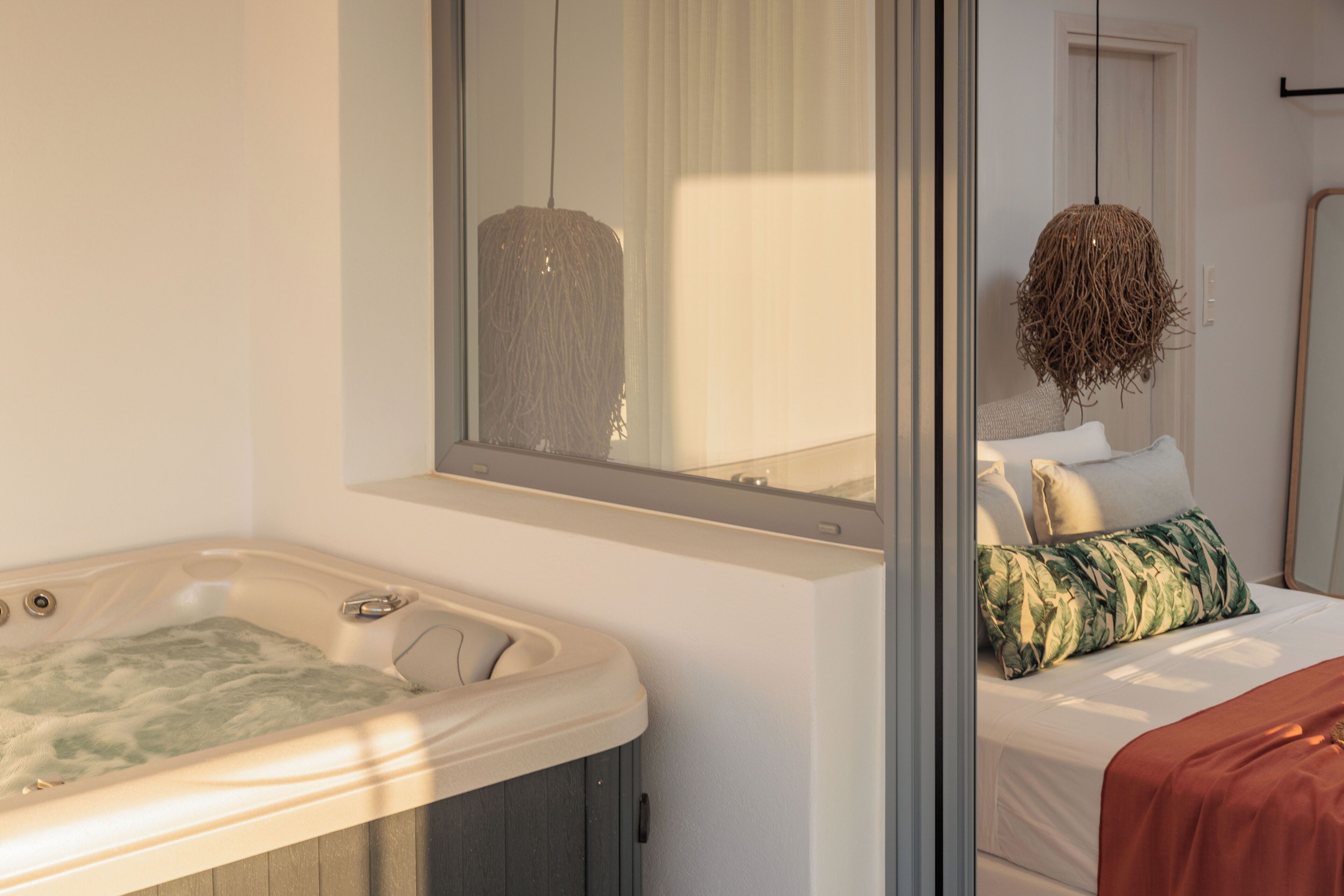 A modern bathroom with a large mirror, a bathtub, and a bed with a hanging light fixture.