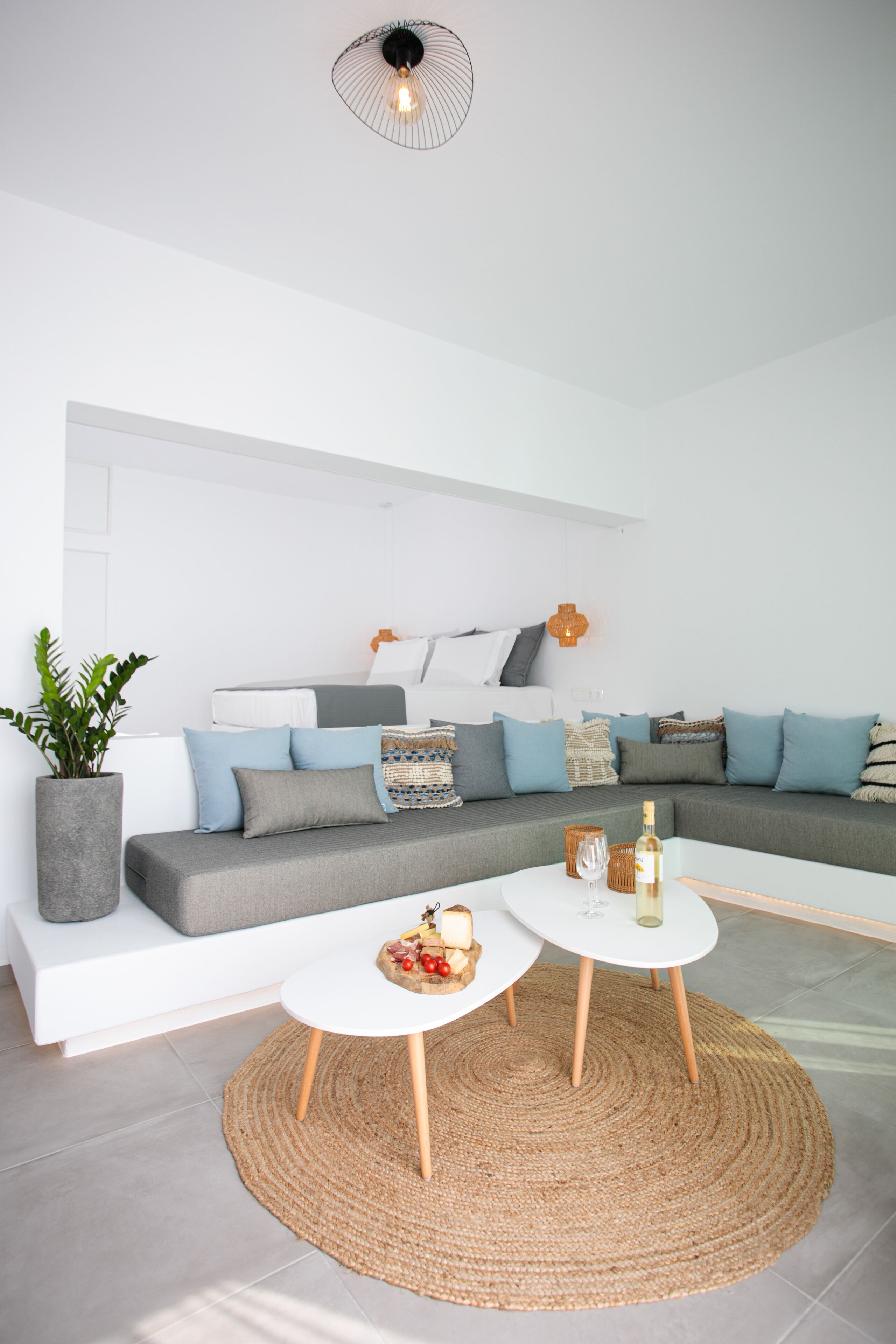 A modern living room with a grey sofa, white coffee table, and a woven rug.