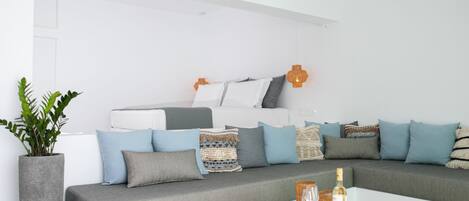 A modern living room with a grey sofa, white coffee table, and a woven rug.