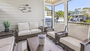A covered outdoor seating area with wicker furniture, a decorative wall, and a view of neighboring houses. - 3 Shore Crest, Chefs Kitchen, Free Golf, Game Room, Beach, Pool (Hilton Head)