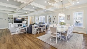 A spacious living room with a large TV, comfortable seating, and a dining area with a white table and chairs. - 3 Shore Crest, Chefs Kitchen, Free Golf, Game Room, Beach, Pool (Hilton Head)