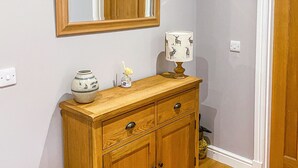 Un mobiletto in legno con due cassetti e un vaso con un fiore sopra.