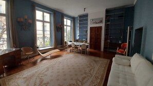 A living room with a large rug, a white sofa, a dining table with chairs, and a bookshelf. - Italian designed apartment Marais (Paris)