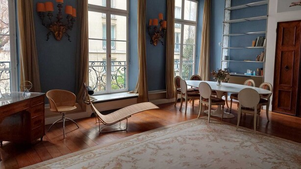 A dining room with a table set for four, a sofa, and a bookshelf. - Italian designed apartment Marais (Paris)