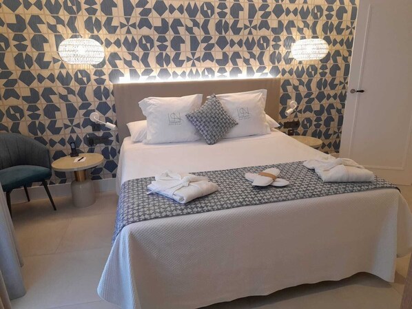 Una cama bien hecha con un edredón estampado, dos almohadas y una mesita de noche con una lámpara.