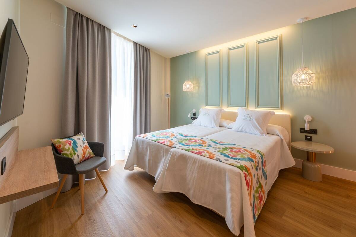Una habitació d'hotel amb un llit gran, un escriptori, una cadira i una televisió.