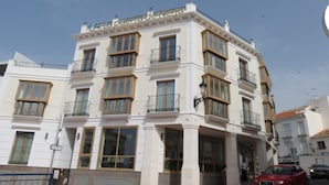 Un edificio de varios pisos con fachada blanca, varios balcones y ventanas amplias.