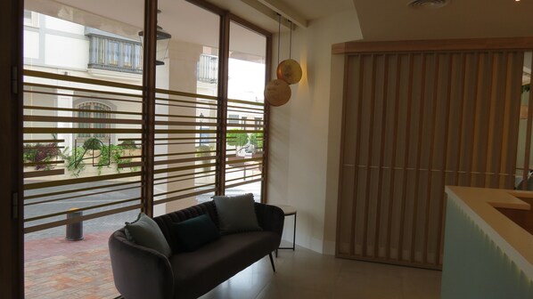 A modern living room with a sofa, a wooden partition, and a view of the outside. - La Puerta de Nerja Hostal Boutique (Nerja)