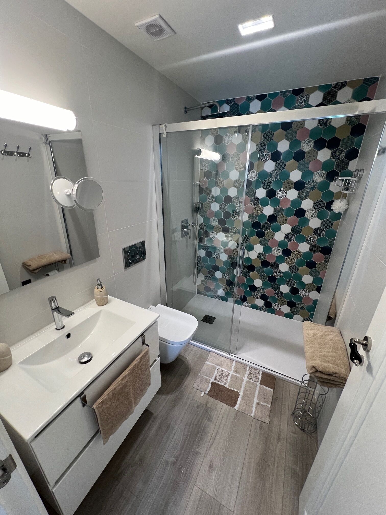 Un baño moderno con cabina de ducha de vidrio, un lavabo blanco y un inodoro.