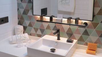 A bathroom with a white sink, a mirror, and a geometric-patterned wall.