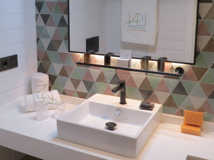 A bathroom with a white sink, a mirror, and a geometric-patterned wall.