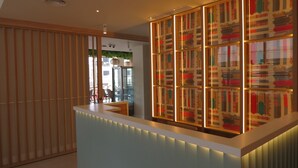 Un área de recepción de diseño moderno, con un mostrador de recepción y un panel decorativo con motivos artísticos.