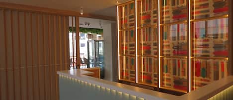 A reception area with a modern design, featuring a reception desk and a decorative panel with patterned artwork.