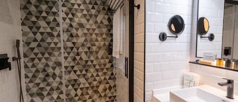 A modern bathroom with a geometric patterned shower enclosure, a white sink with a mirror, and a towel rack.