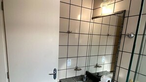 A bathroom with a white sink, a mirror, a toilet, and a glass shower enclosure. - Diroma Fiori - JC TEMPORADA (Caldas Novas)